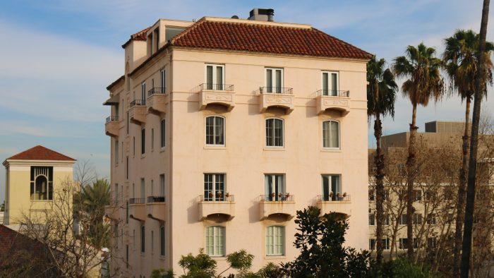beige concrete building near green trees under blue sky during daytime